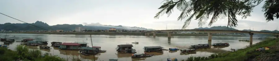 A panorama of house boats floating next to a bridge on the Song Da river in Hoa Binh 