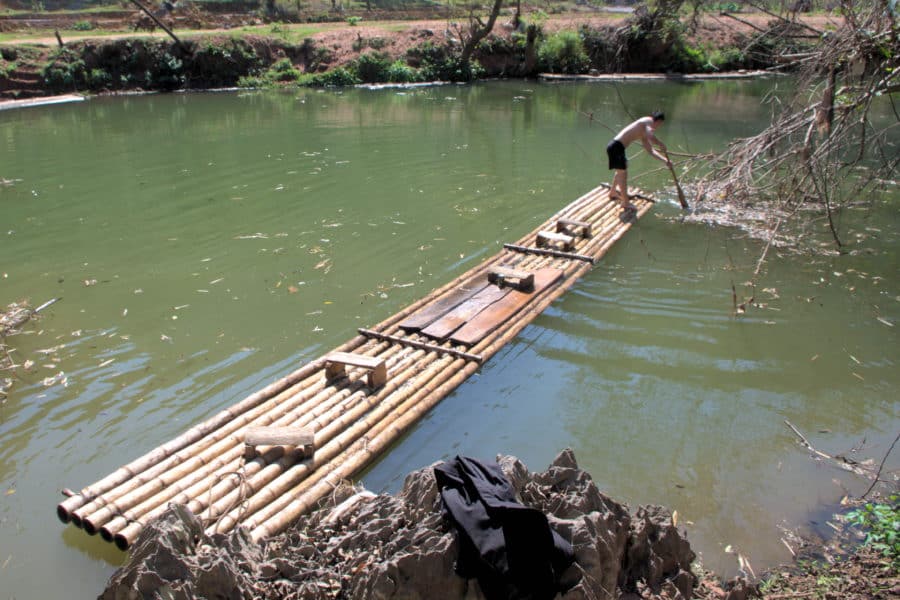 Thai man paddling a bamboo raft on the Ma stream