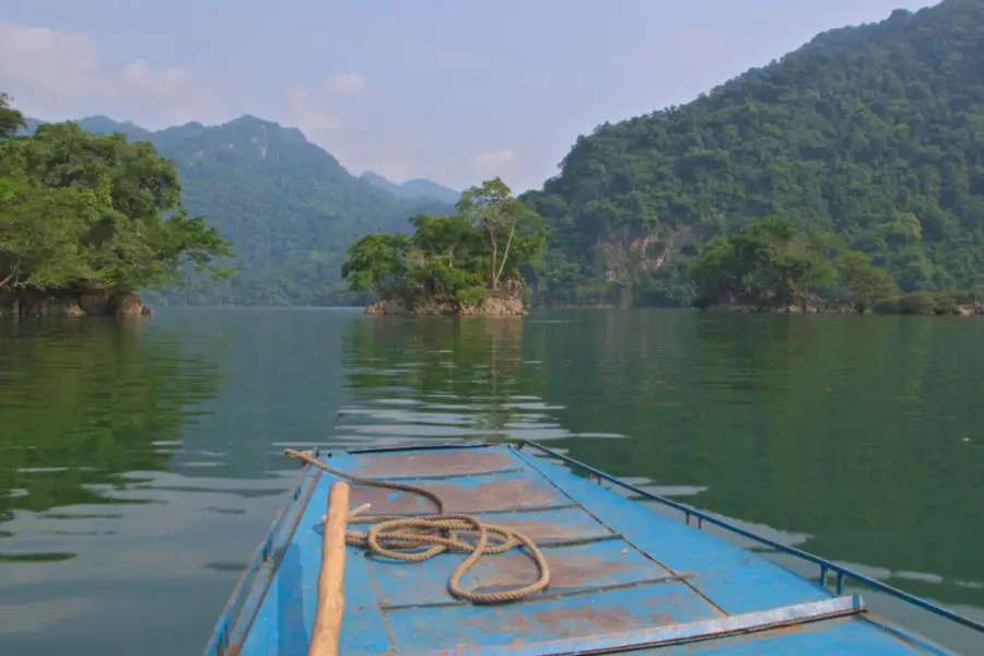 The front of a blue boat with a coil of rope as it tours across Ba Be lake