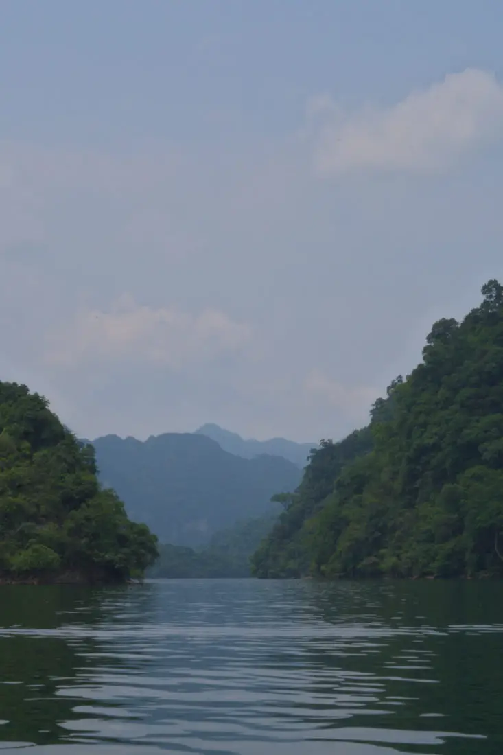 A view of Ba Be lake from a boat tour as it's still waters are wedged between lush green mountains.