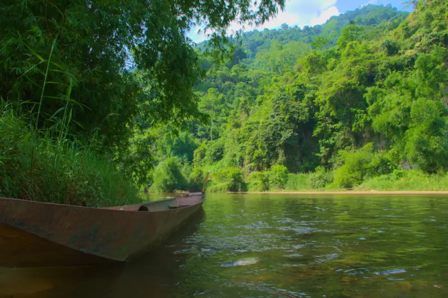 A wooden canoe floatingon a peaceful stream at the edge of Ba Be lake