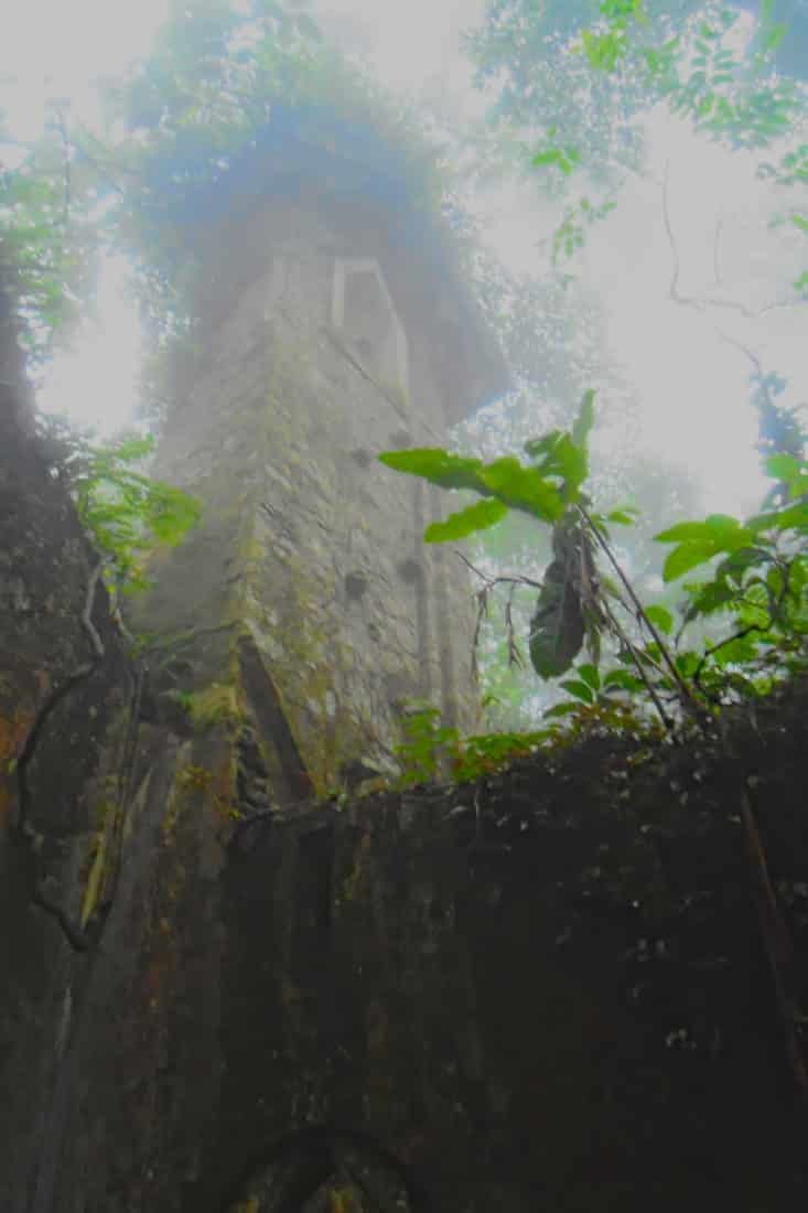 Looking up through the fog at a ruined French colonial church tower in the jungle of Ba Vi mountain