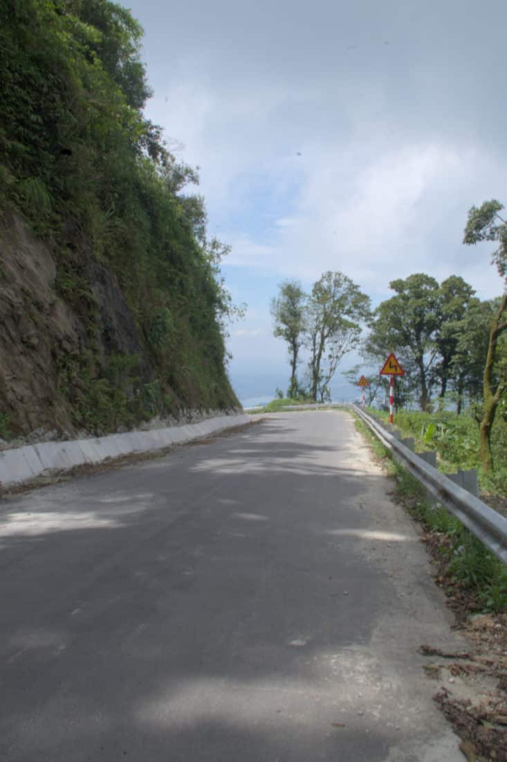 A paved road descending a mountain motorcycle tour with a guardrail on the right