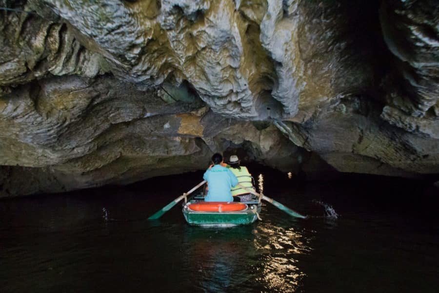 A boat ebtering a low cave in Trang An, Ninh Binh