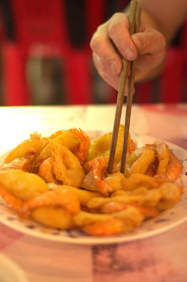 A pair of chopsticks picking up Vietnamese prawn fritters 