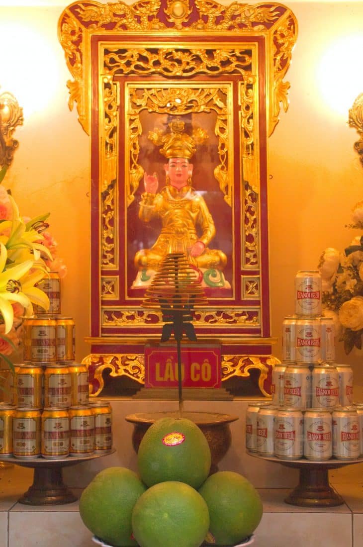 A small veitnamese shrine with grapefruit and beer offerings