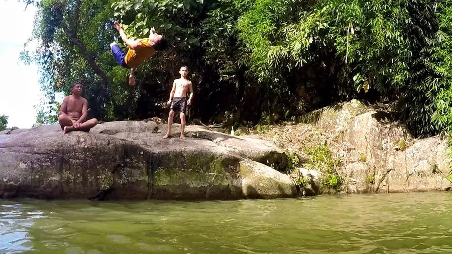 A man doing a backflip of a rock into water