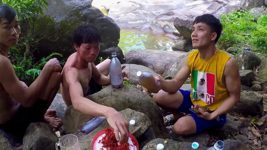 Vietnamese men drinking beer on rocks beside a stream