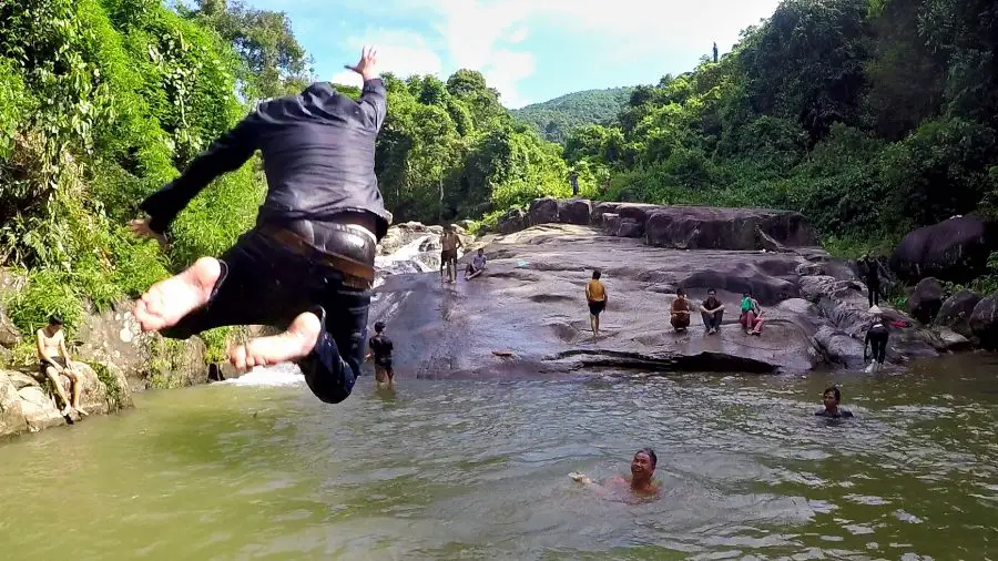 A man jumping into a stream with jeans on in Vietnam