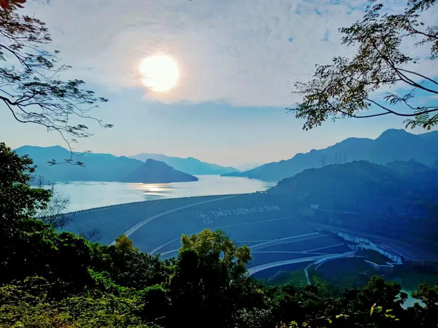 A huge dam and resevior with mountains in the background