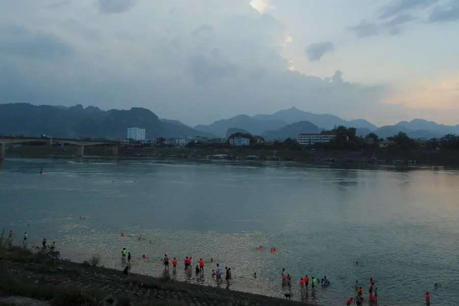 Popel swimming with life jackets at a river at dusk